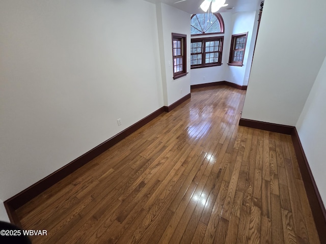 empty room featuring a barn door, baseboards, and dark wood-style flooring