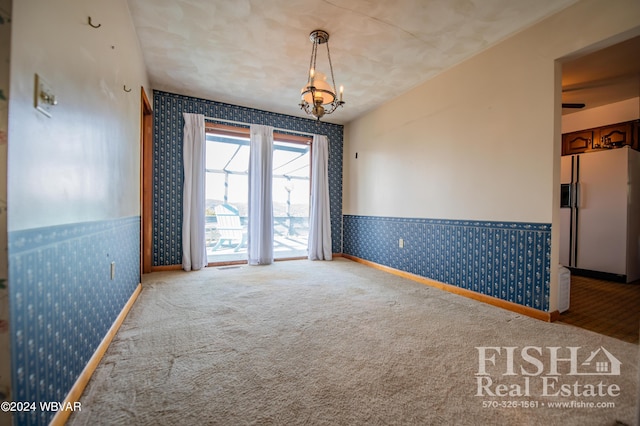 carpeted empty room with a chandelier