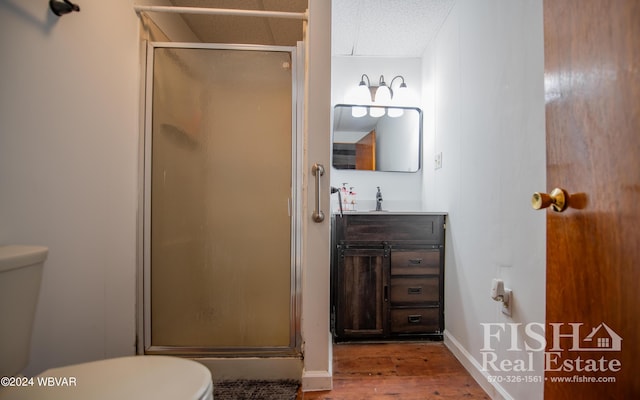 bathroom with a textured ceiling, vanity, hardwood / wood-style flooring, toilet, and a shower with shower door