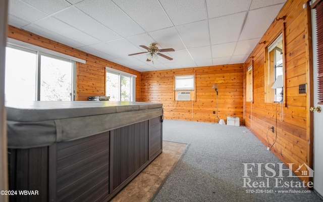 interior space with wood walls, a drop ceiling, cooling unit, and ceiling fan