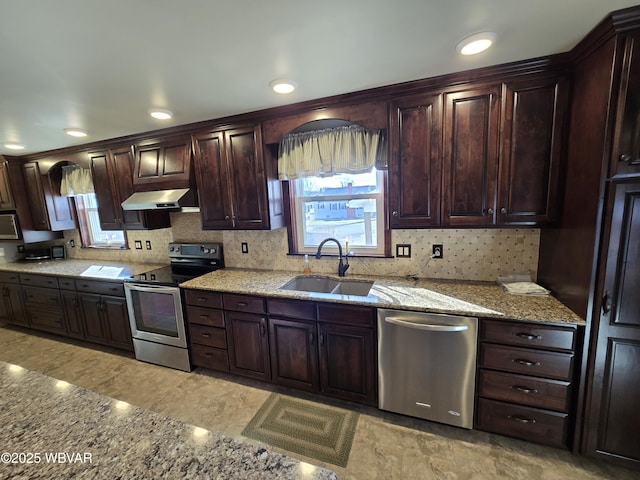 kitchen featuring light stone countertops, dark brown cabinets, stainless steel appliances, exhaust hood, and sink