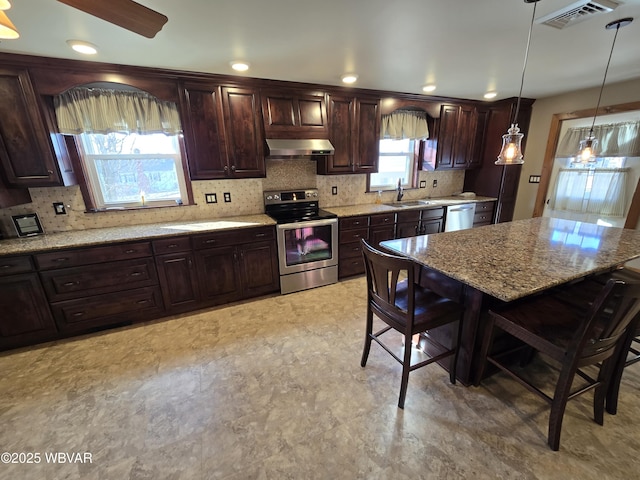 kitchen featuring appliances with stainless steel finishes, a breakfast bar, sink, exhaust hood, and pendant lighting