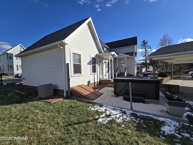 rear view of house with a patio area, a yard, and a hot tub