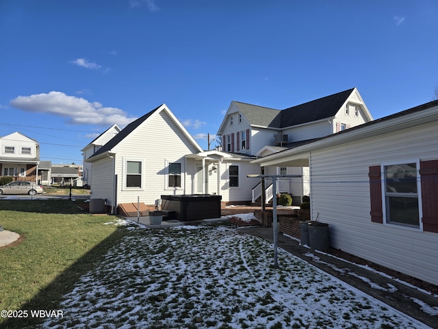 rear view of house with a yard, a hot tub, and central AC unit