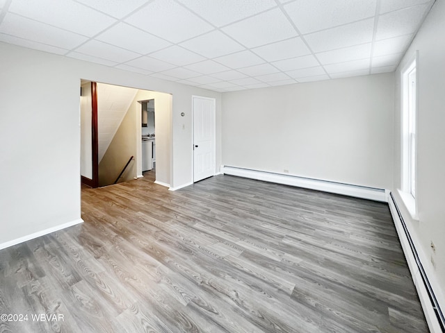 spare room with hardwood / wood-style flooring, a drop ceiling, and a baseboard radiator