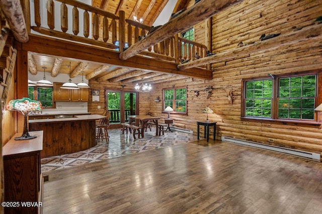 175 Hemlock Ln, Millville, PA 17846 - dining space with baseboard heating, wood-type flooring, log walls, plenty of natural light, and a high ceiling