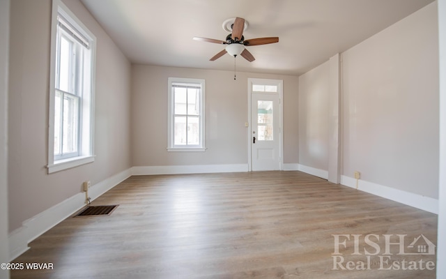unfurnished room featuring a ceiling fan, baseboards, visible vents, and wood finished floors