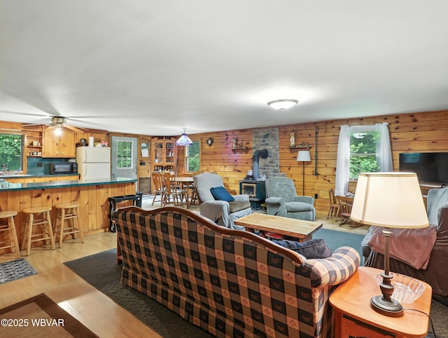 72 Carl Rd, Dushore, PA 18614 - living area featuring a wood stove, healthy amount of natural light, wooden walls, and light wood-style flooring