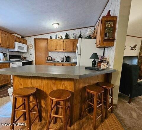 68 Sassafras Ln, Waterville, PA 17776 - kitchen with decorative backsplash, a peninsula, white appliances, a breakfast bar, and brown cabinets