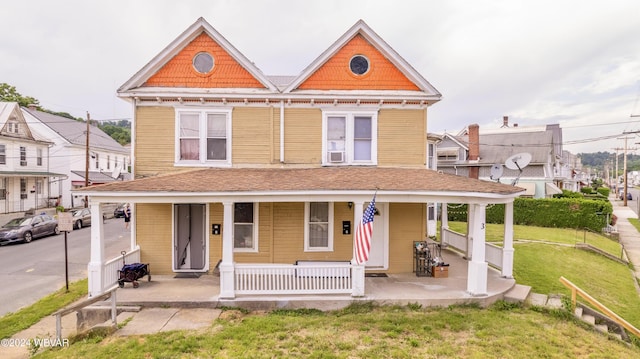 victorian house featuring covered porch and a front lawn