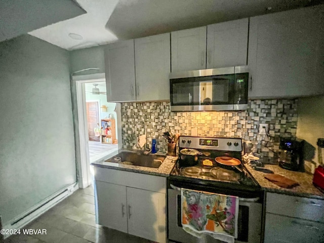 kitchen with sink, stainless steel appliances, dark stone countertops, decorative backsplash, and white cabinets