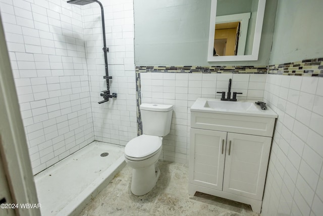 bathroom featuring a tile shower, vanity, tile walls, and toilet