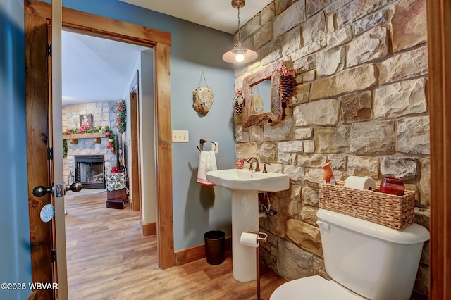 bathroom featuring hardwood / wood-style floors, a fireplace, and toilet