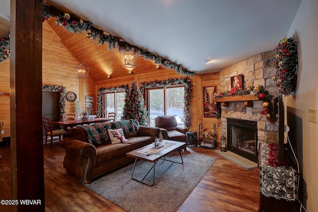 living room featuring lofted ceiling, a stone fireplace, hardwood / wood-style floors, and wood walls