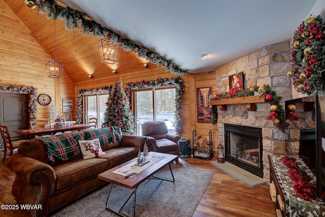 living room with a fireplace, wooden walls, lofted ceiling, a chandelier, and hardwood / wood-style flooring