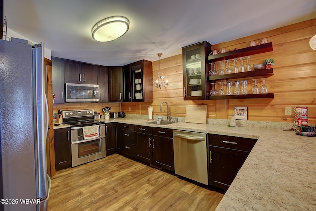 kitchen with sink, dark brown cabinets, stainless steel appliances, decorative light fixtures, and light wood-type flooring