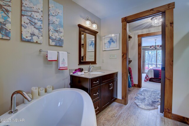 bathroom featuring vanity, a chandelier, and a bathtub