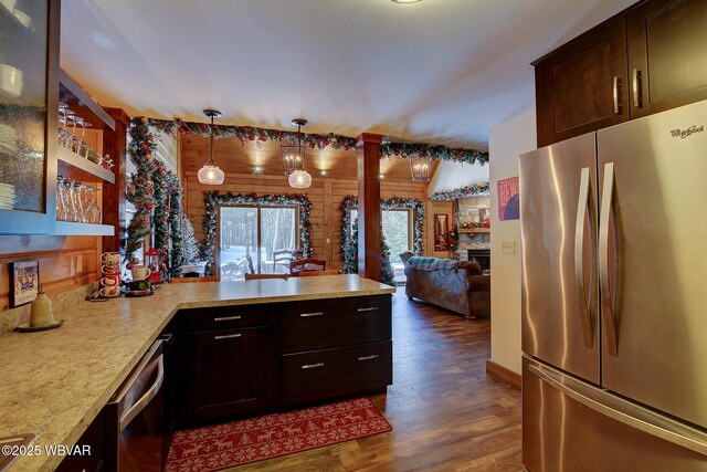 kitchen with pendant lighting, a fireplace, dark brown cabinetry, stainless steel appliances, and dark wood-type flooring