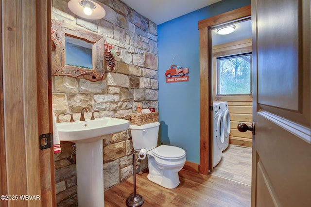 bathroom featuring hardwood / wood-style floors, sink, washer and dryer, and toilet