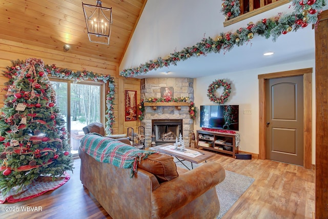 living room featuring wood ceiling, hardwood / wood-style flooring, an inviting chandelier, high vaulted ceiling, and a fireplace