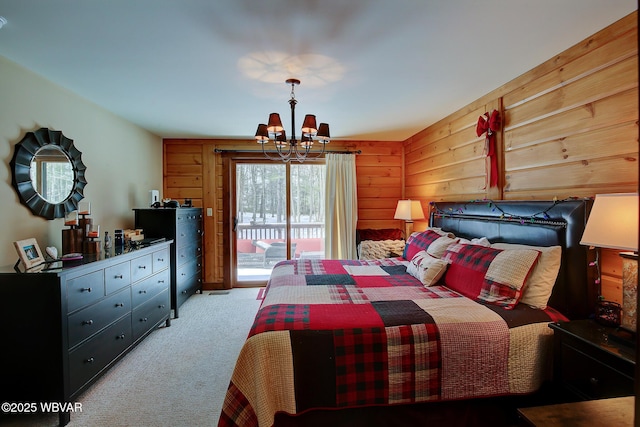 carpeted bedroom featuring access to exterior, wooden walls, and a chandelier