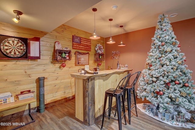 bar featuring hardwood / wood-style flooring, pendant lighting, and wood walls