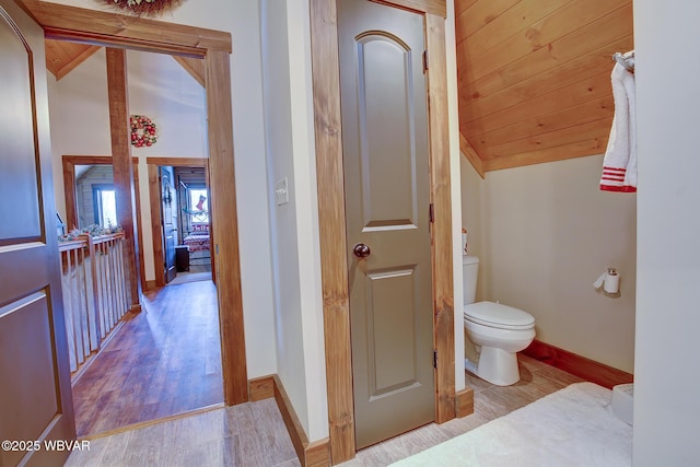 bathroom with hardwood / wood-style flooring, lofted ceiling, wooden ceiling, and toilet