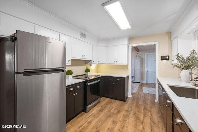 kitchen with sink, white cabinets, stainless steel appliances, and light wood-type flooring