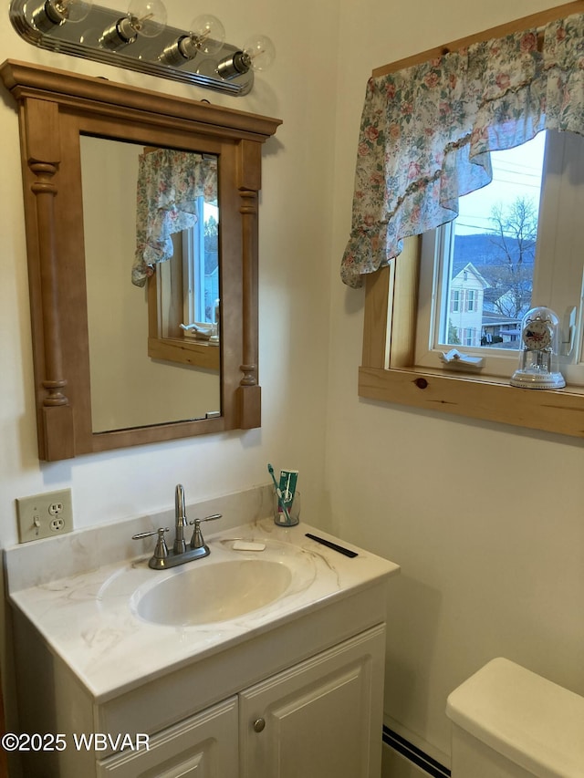 bathroom with baseboard heating, vanity, and toilet