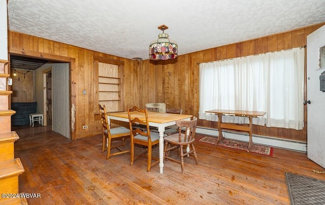 dining room featuring hardwood / wood-style floors, baseboard heating, and wooden walls