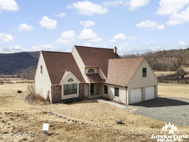 view of front of home with a garage, gravel driveway, roof with shingles, and a chimney