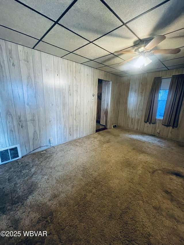 empty room featuring visible vents, a paneled ceiling, and carpet