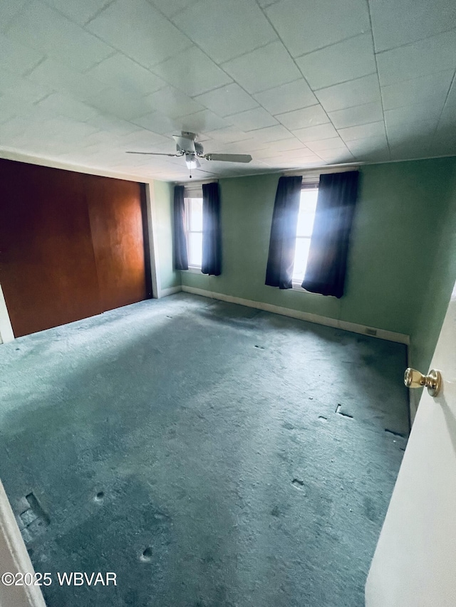 interior space with a ceiling fan, baseboards, and carpet floors