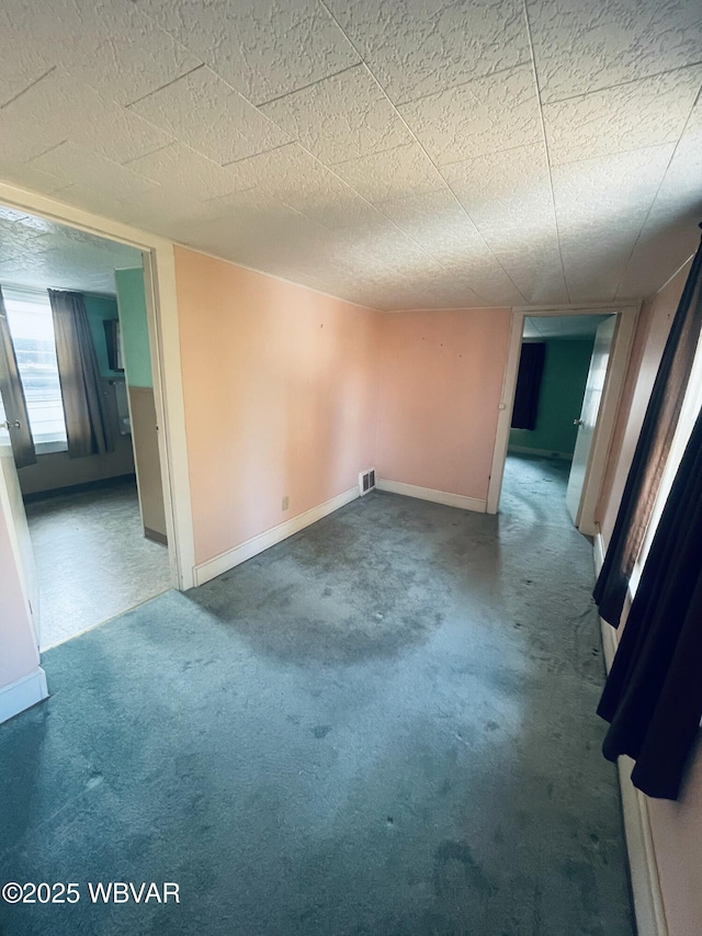 empty room featuring visible vents, carpet, and baseboards