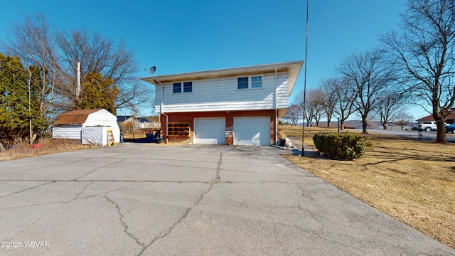 view of property exterior featuring a storage unit, a garage, brick siding, and driveway