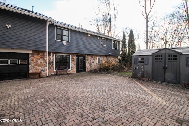 rear view of property featuring a garage and a storage unit