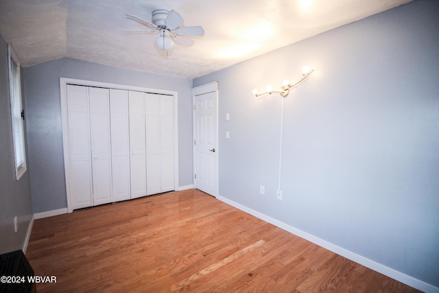 unfurnished bedroom with hardwood / wood-style floors, ceiling fan, vaulted ceiling, and a closet