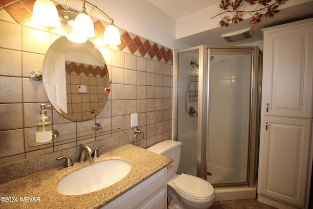 bathroom featuring tasteful backsplash, vanity, a shower with shower door, and toilet