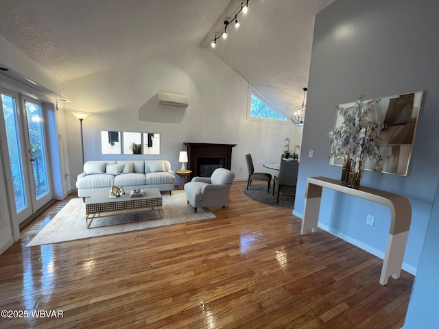 living room with a wealth of natural light, hardwood / wood-style floors, track lighting, and an inviting chandelier