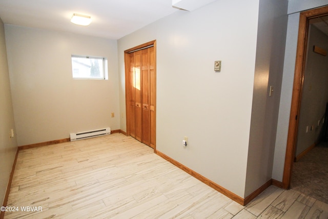spare room with a baseboard radiator, light wood-style floors, and baseboards