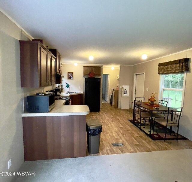 kitchen featuring black fridge, crown molding, dark brown cabinetry, light wood-type flooring, and kitchen peninsula