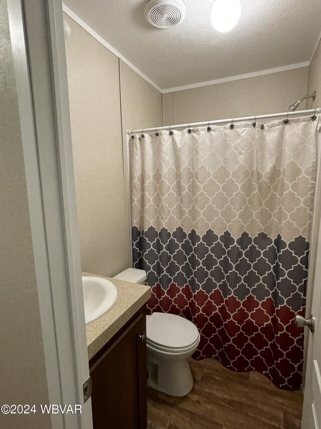 bathroom featuring vanity, a textured ceiling, crown molding, hardwood / wood-style floors, and toilet