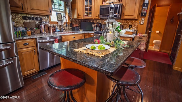 196 Shawnee Dr, Muncy, PA 17756 - kitchen with appliances with stainless steel finishes, a sink, dark wood-style flooring, a kitchen breakfast bar, and decorative backsplash