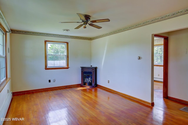 443 Derr Hill Rd, Lock Haven, PA 17745 - unfurnished room featuring a baseboard radiator, a wood stove, a ceiling fan, wood finished floors, and baseboards