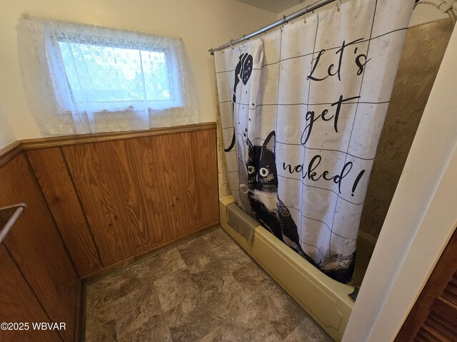 full bathroom with shower / bath combo, a wainscoted wall, and wooden walls