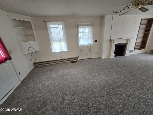 unfurnished living room with built in shelves, a baseboard heating unit, a fireplace, baseboards, and carpet