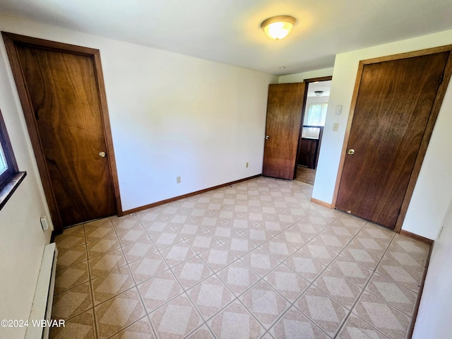 unfurnished bedroom featuring baseboard heating and baseboards