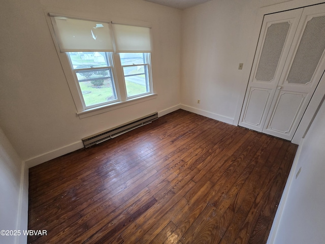 unfurnished bedroom featuring baseboards, a baseboard heating unit, and dark wood finished floors