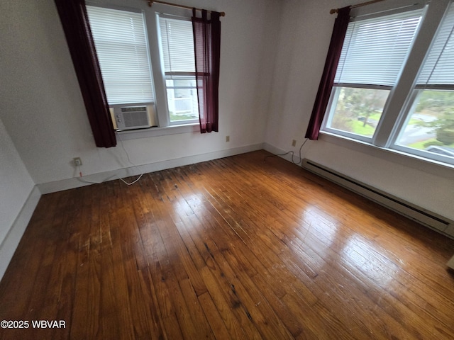 empty room featuring a baseboard heating unit, plenty of natural light, cooling unit, and hardwood / wood-style flooring