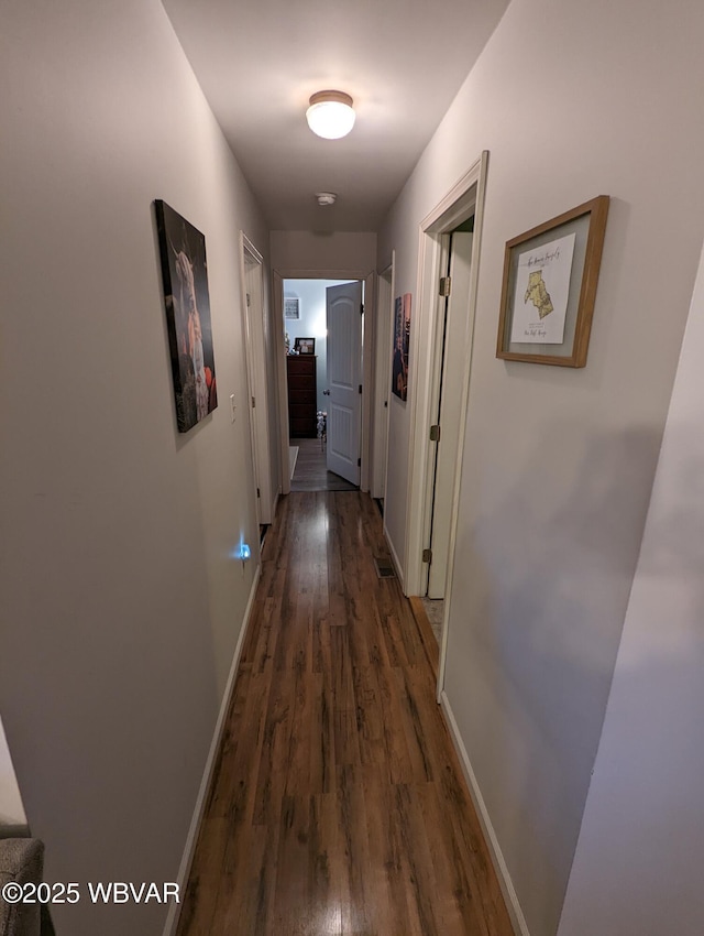 hallway featuring dark wood-style floors and baseboards